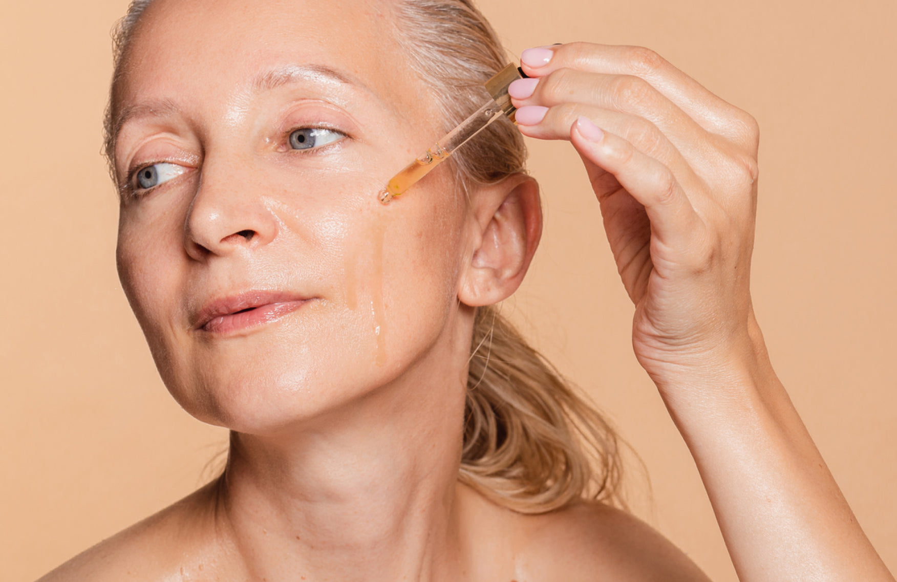 Woman applying a skincare serum with a pipette dropper