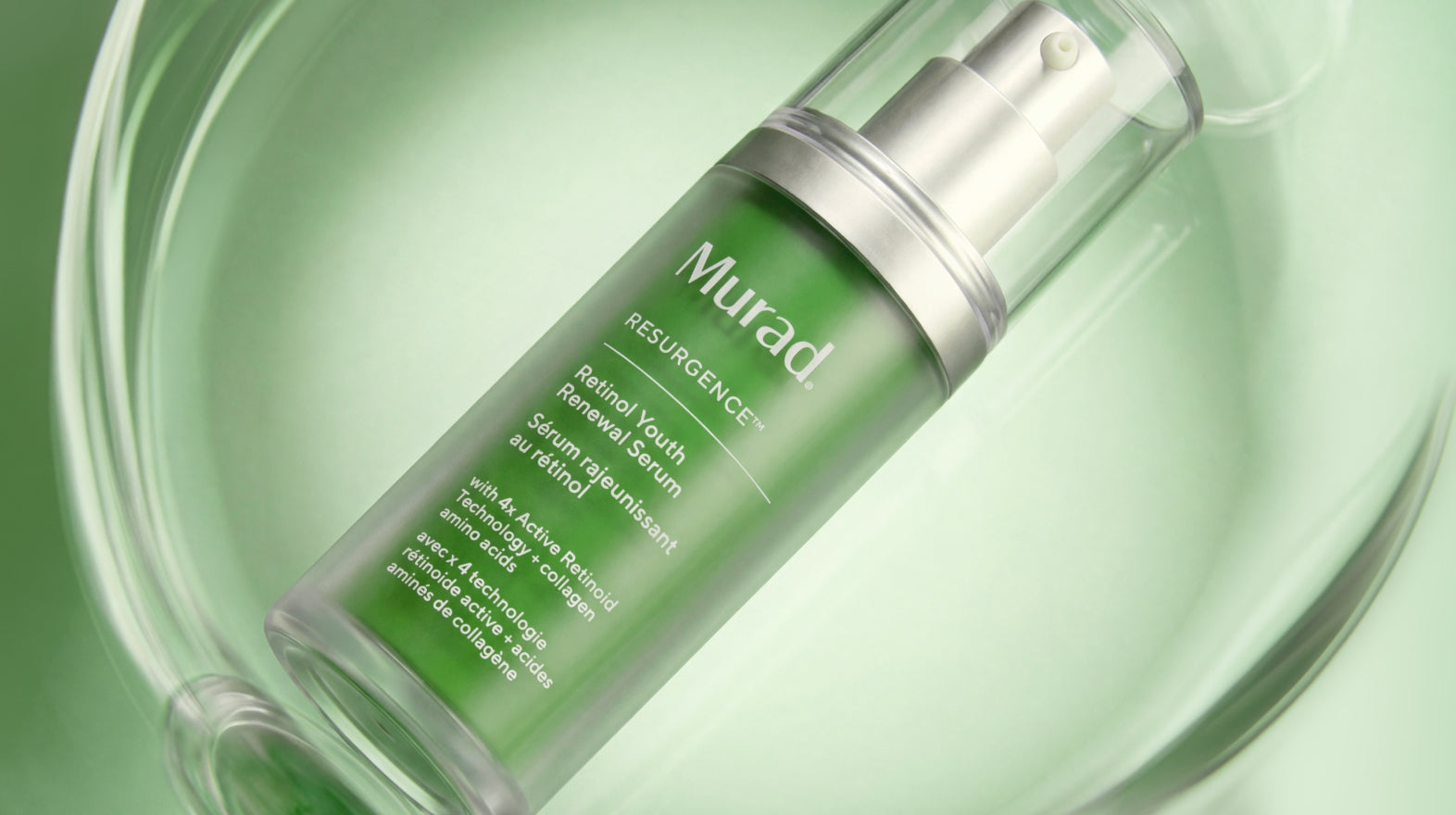 Murad Resurgence Retinol Youth Renewal Serum in a clear bottle with a green liquid and silver pump, resting on a reflective light green surface.