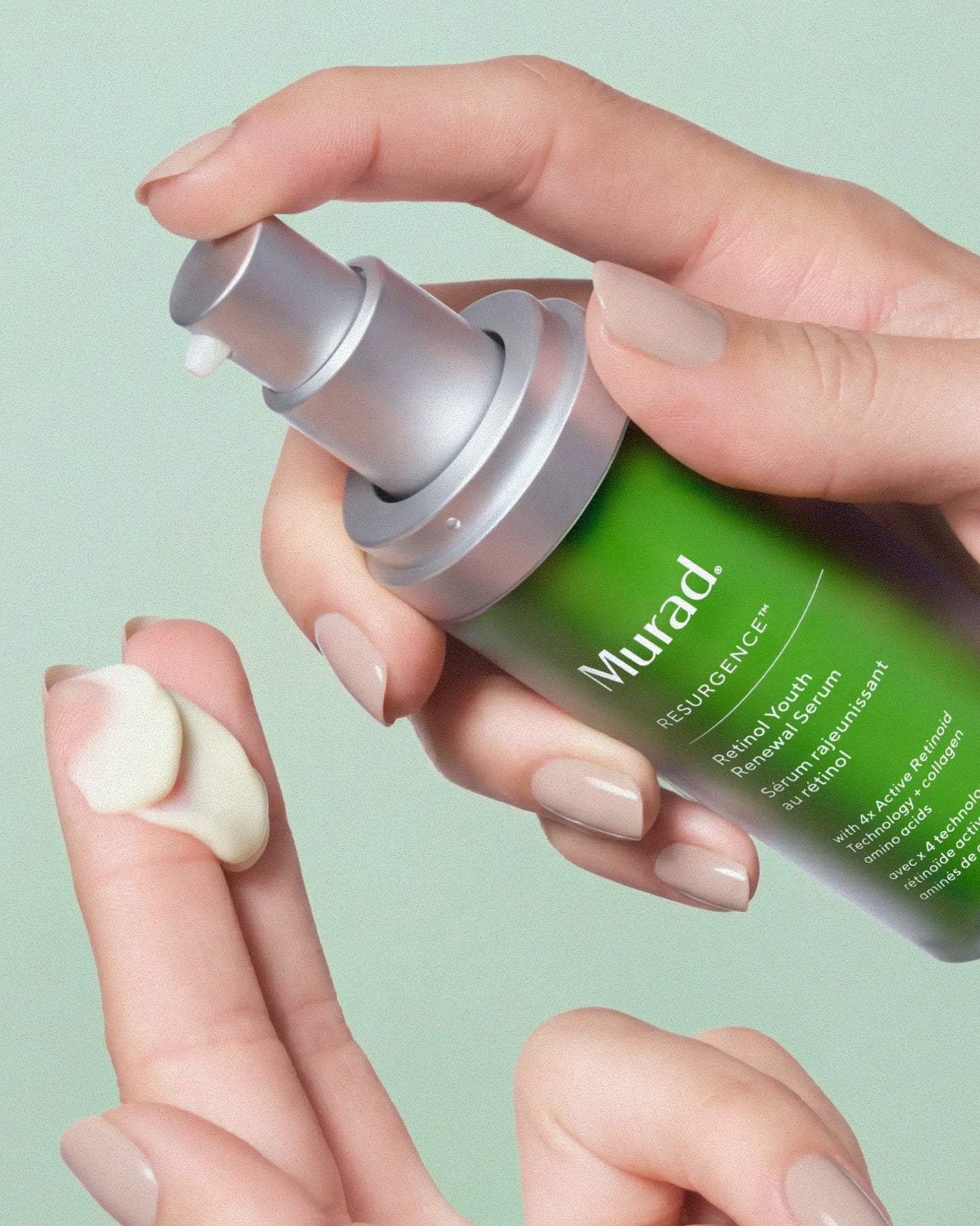 A close-up of hands holding a green and silver Murad Resurgence Facial Youth Serum bottle, with a dollop of the white cream product resting on a finger against a soft mint green background.